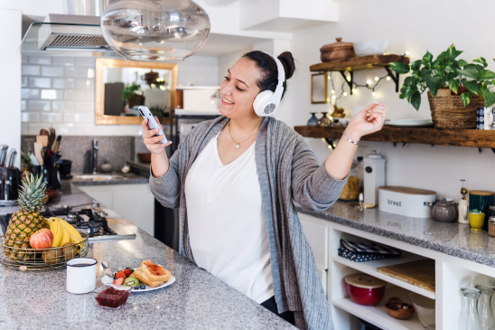 A girl wearing headphones and dancing in a kitchen